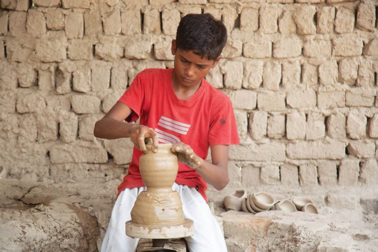Eight-year-old Aslam deftly molds a pot into shape.